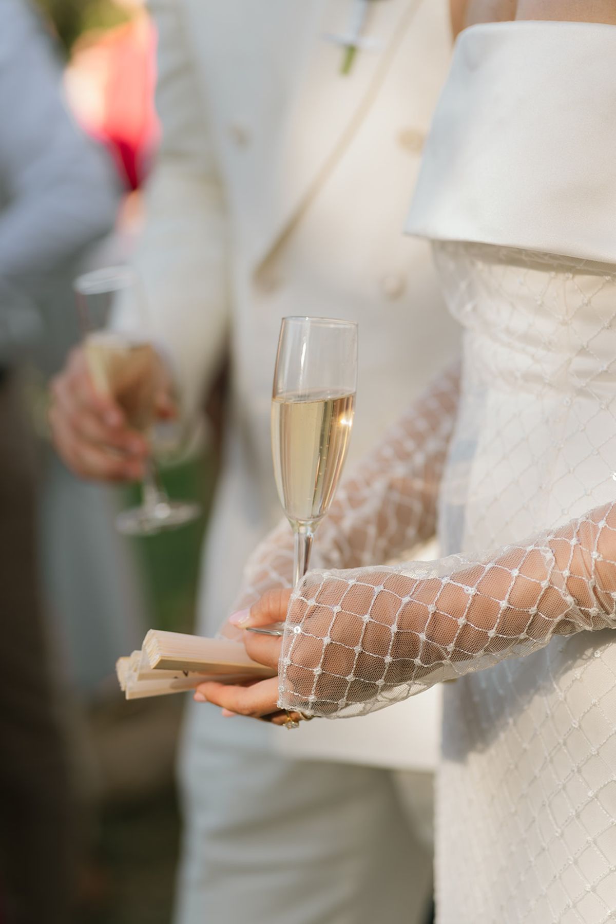 The bride holding a glass of champagne and a folded fan