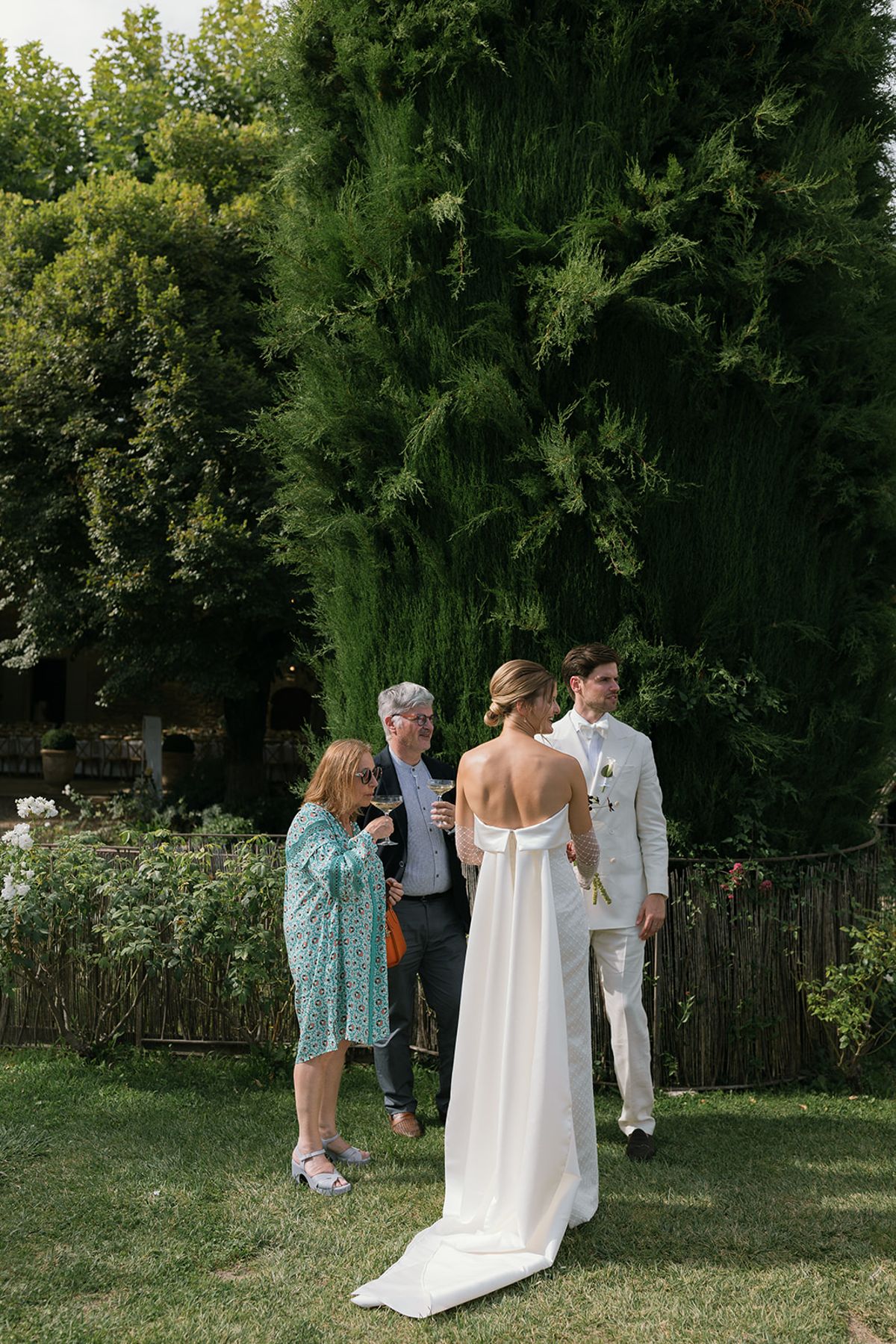 The bride and groom greeting two guests on the lawn