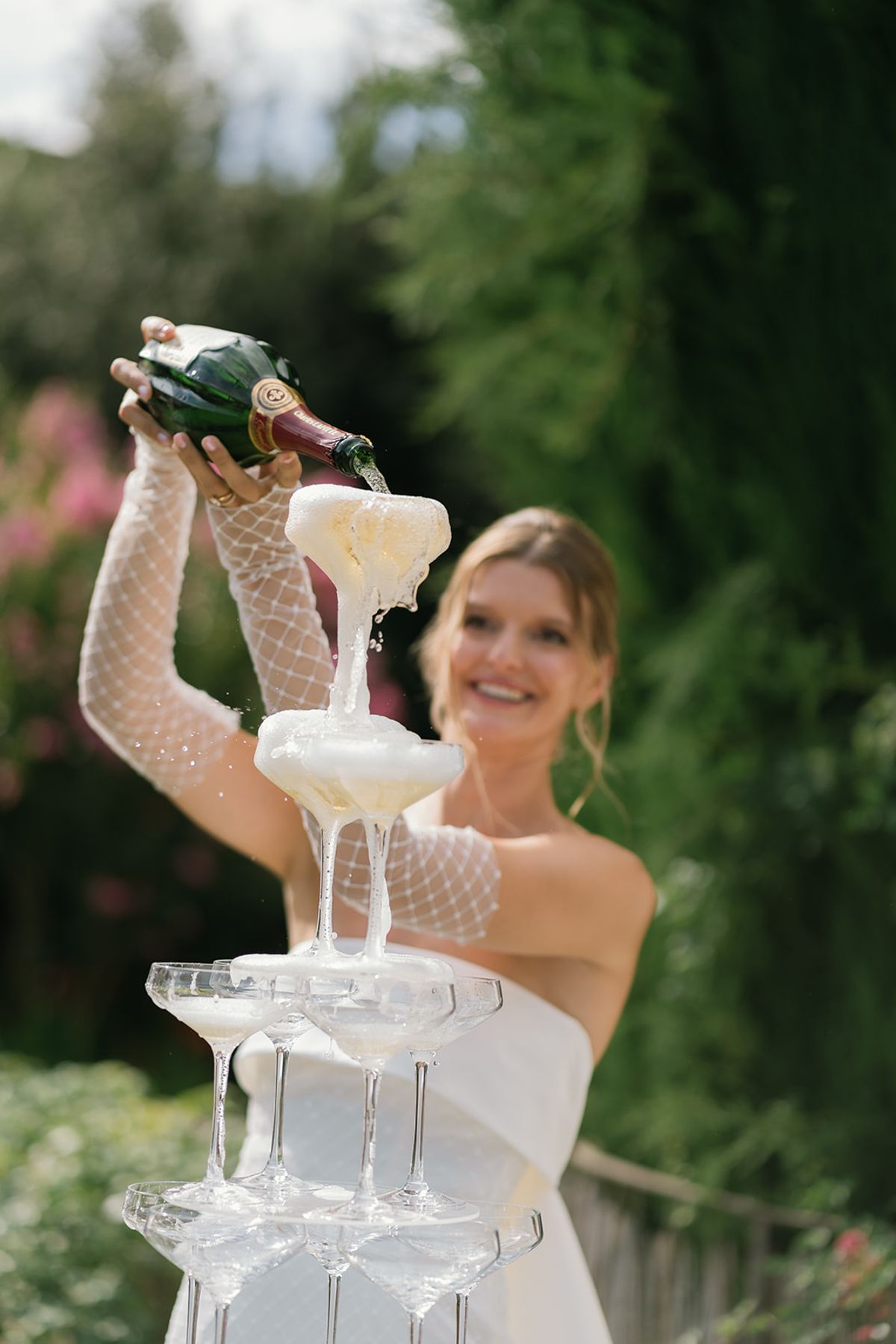 The bride pours champagne into the top of the coupe tower