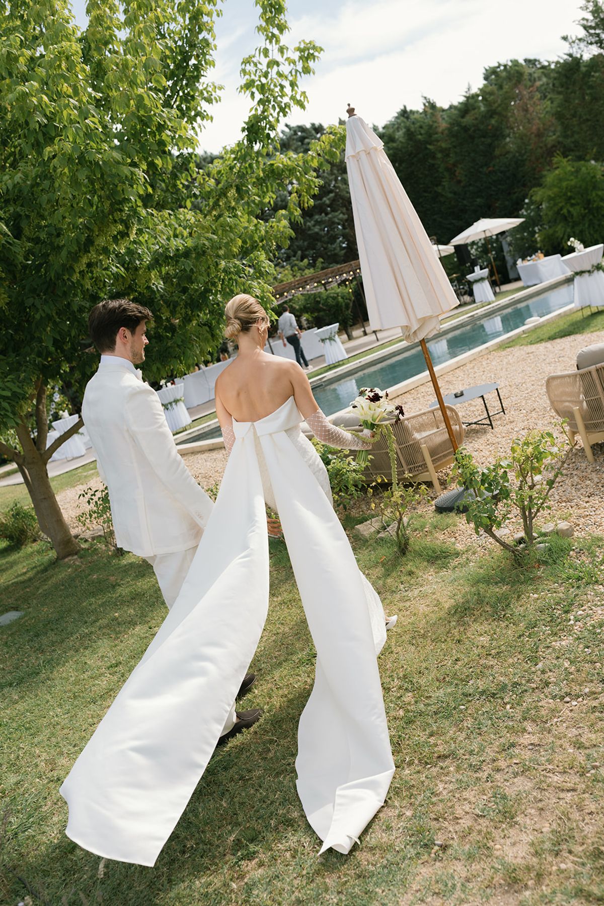 The bride and groom crossing the lawn towards the pool at Le Petit Roulet