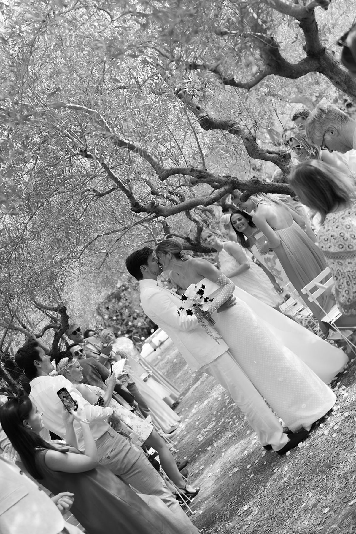 The bride and groom kiss in the aisle as guests stand on either side