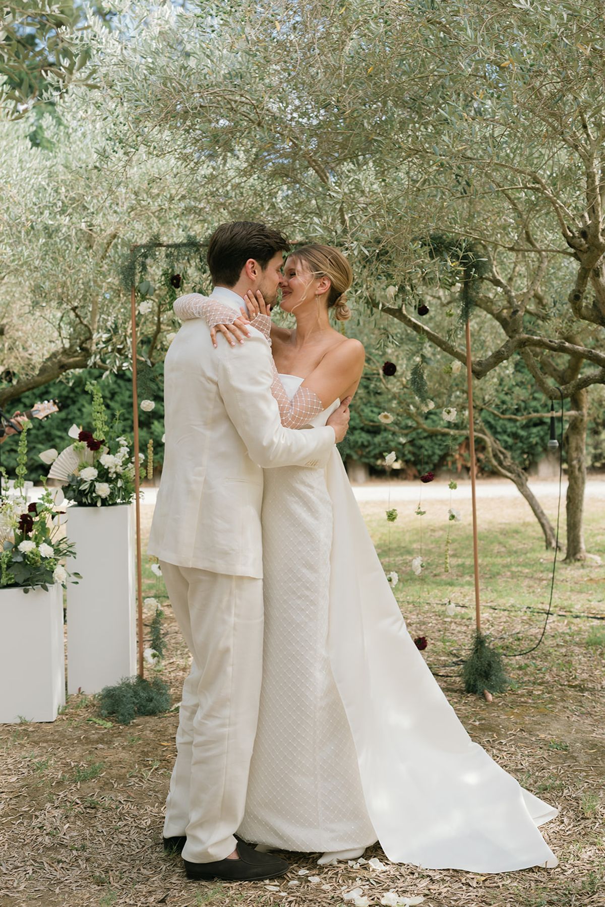 The bride and groom embrace in front of the ceremony arch