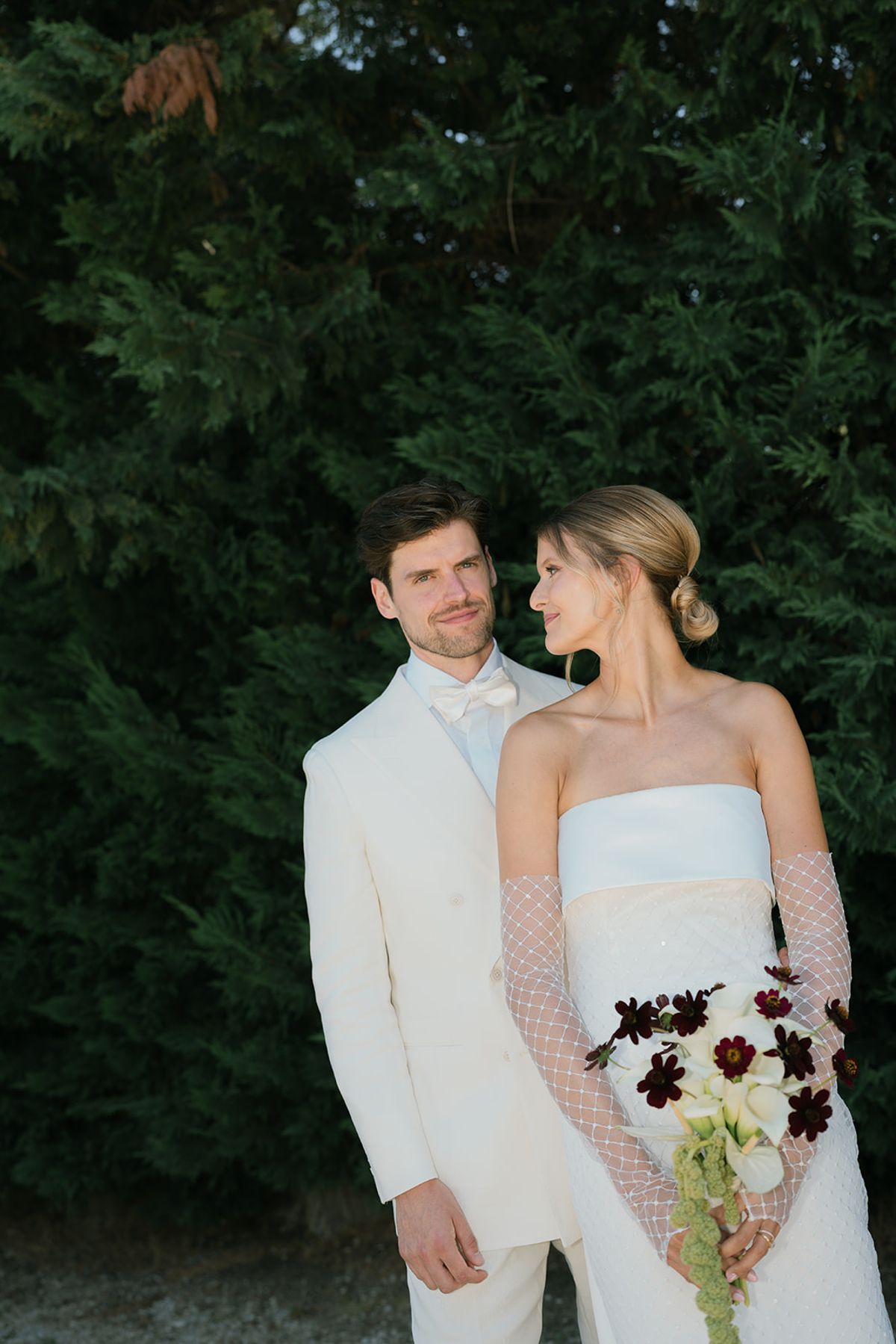 Jolien and Maxime standing together in front of a cypress hedge