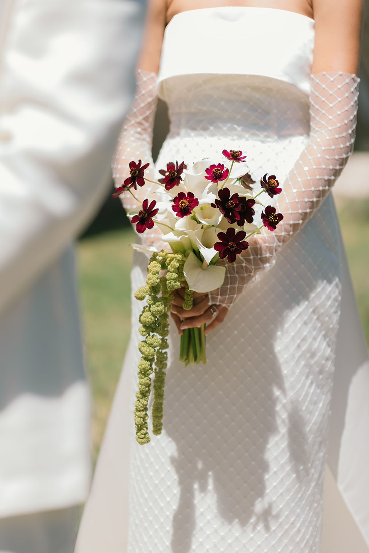 The bride holding her bouquet of dark red cosmos and trailing green amaranthus