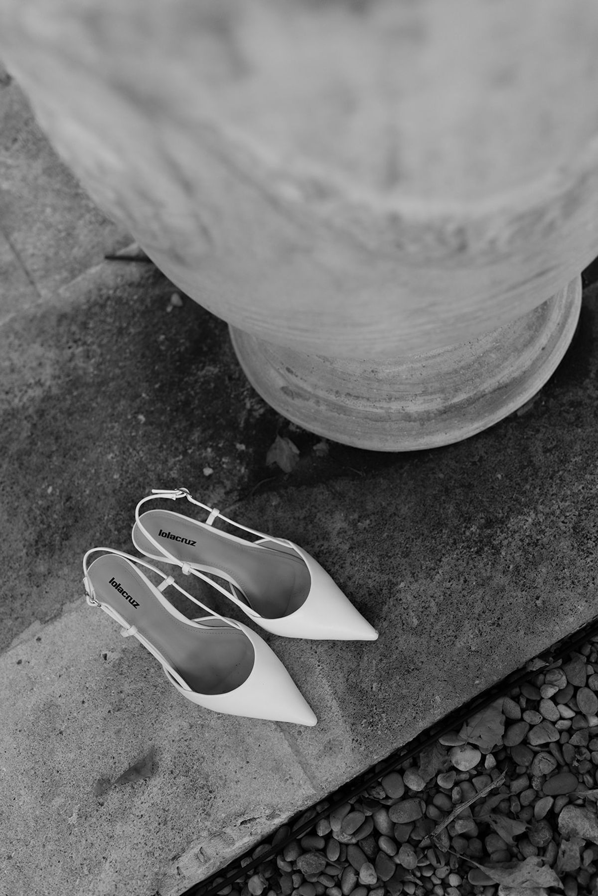 The bride's white pointed shoes on a stone step