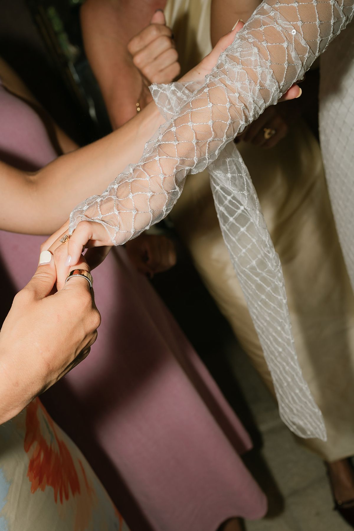 A friend fastens the bride's lattice-pattern sleeve