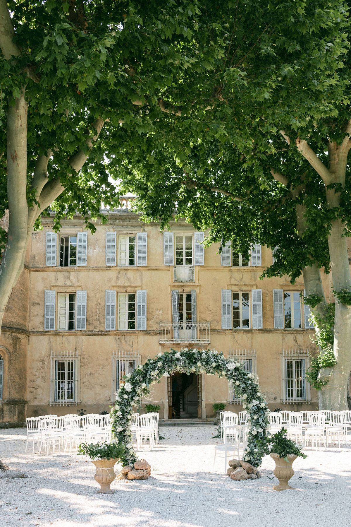The facade of Château de Robernier with the floral ceremony arch and rows of white chairs