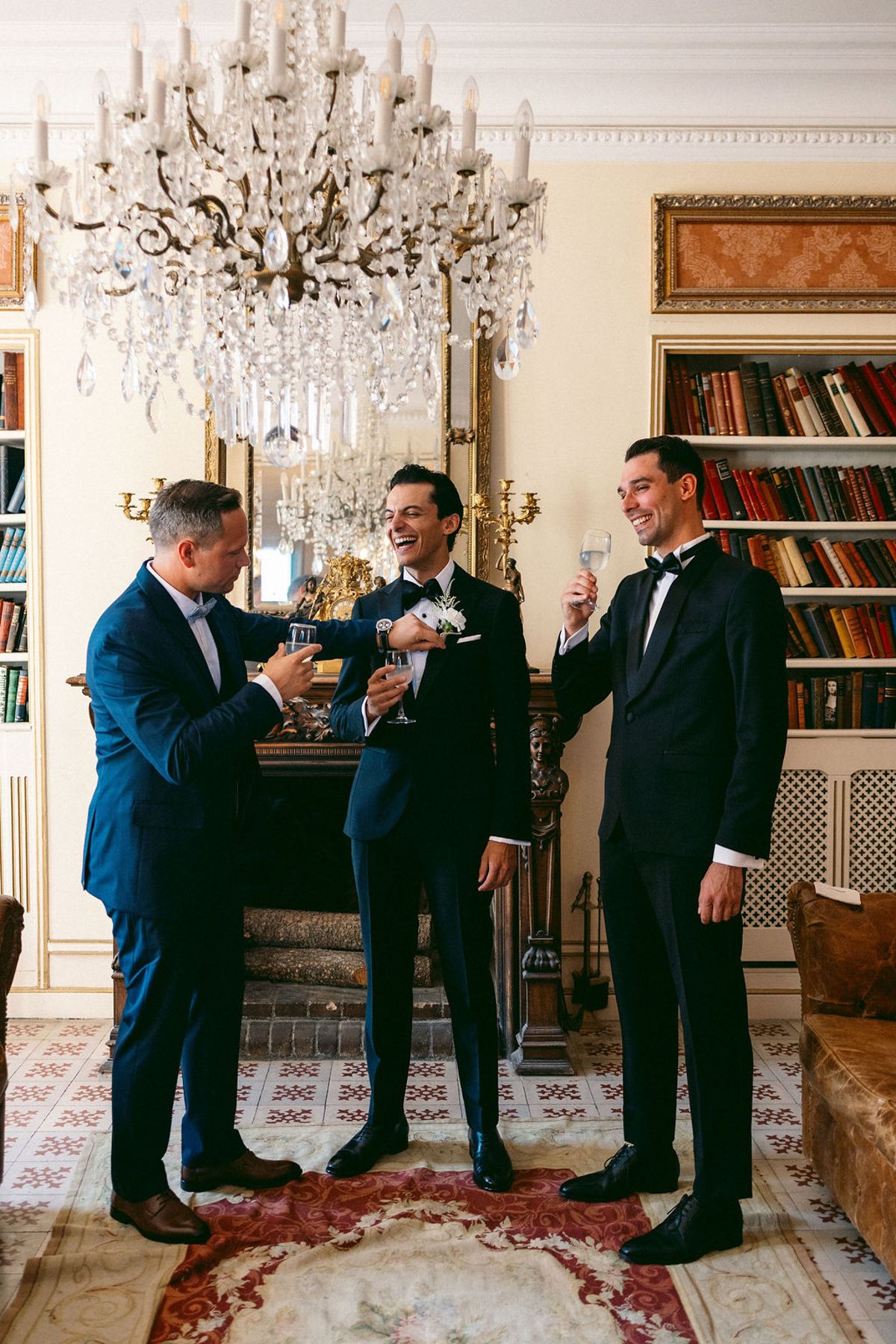 The groom and his groomsmen in a chandelier-lit salon at Château de Robernier