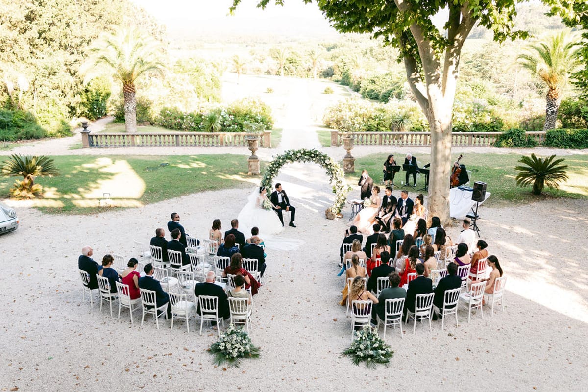 Wide view of the garden ceremony with guests seated before the circular floral arch
