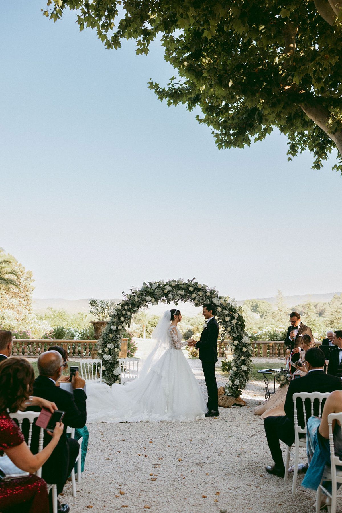 Ilenia and Dalil beneath the floral arch as their guests watch from either side