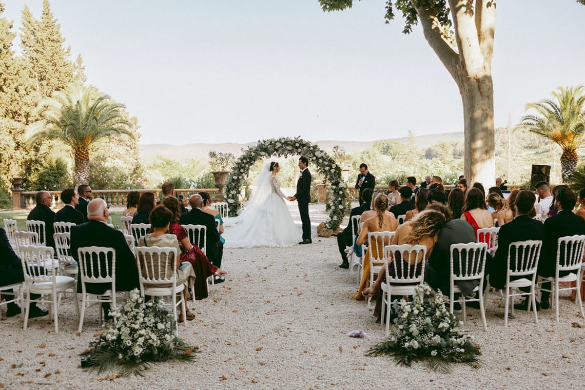 The ceremony aisle and circular floral arch framed by plane trees