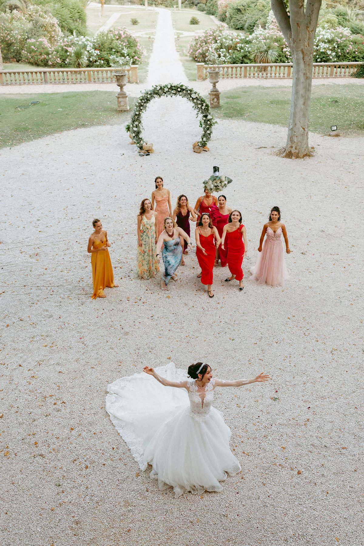 The bride turning in her gown as guests cross the gravel courtyard behind her