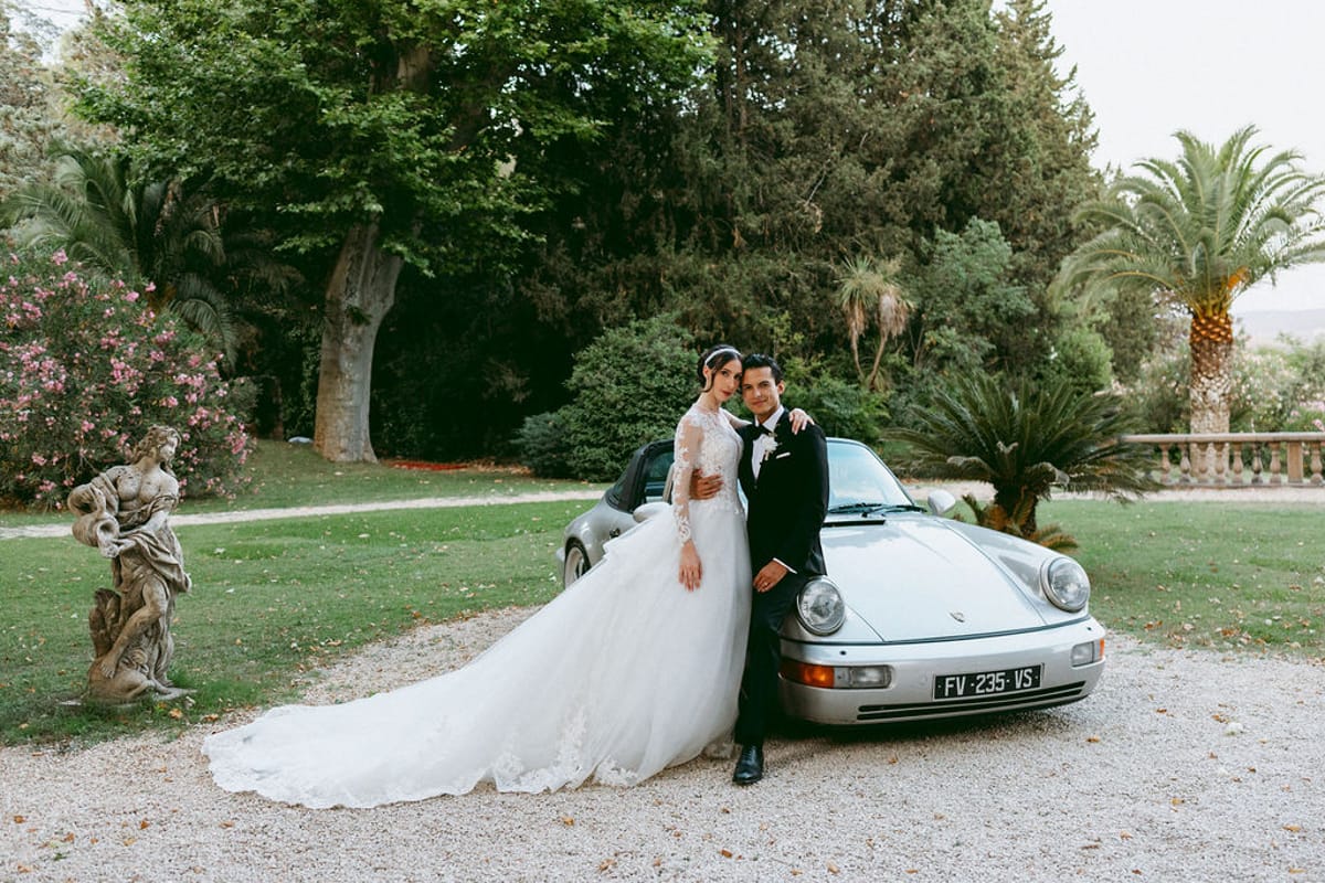 Ilenia and Dalil beside a white convertible in the chateau grounds