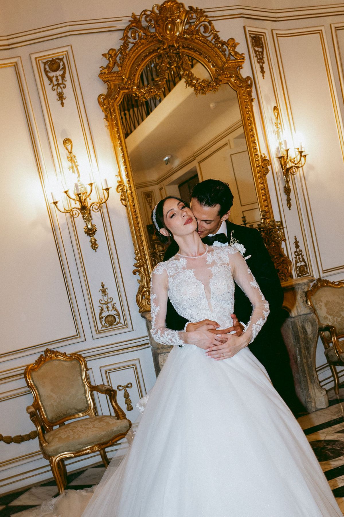 Ilenia and Dalil before a gilded mirror in a salon at Château de Robernier
