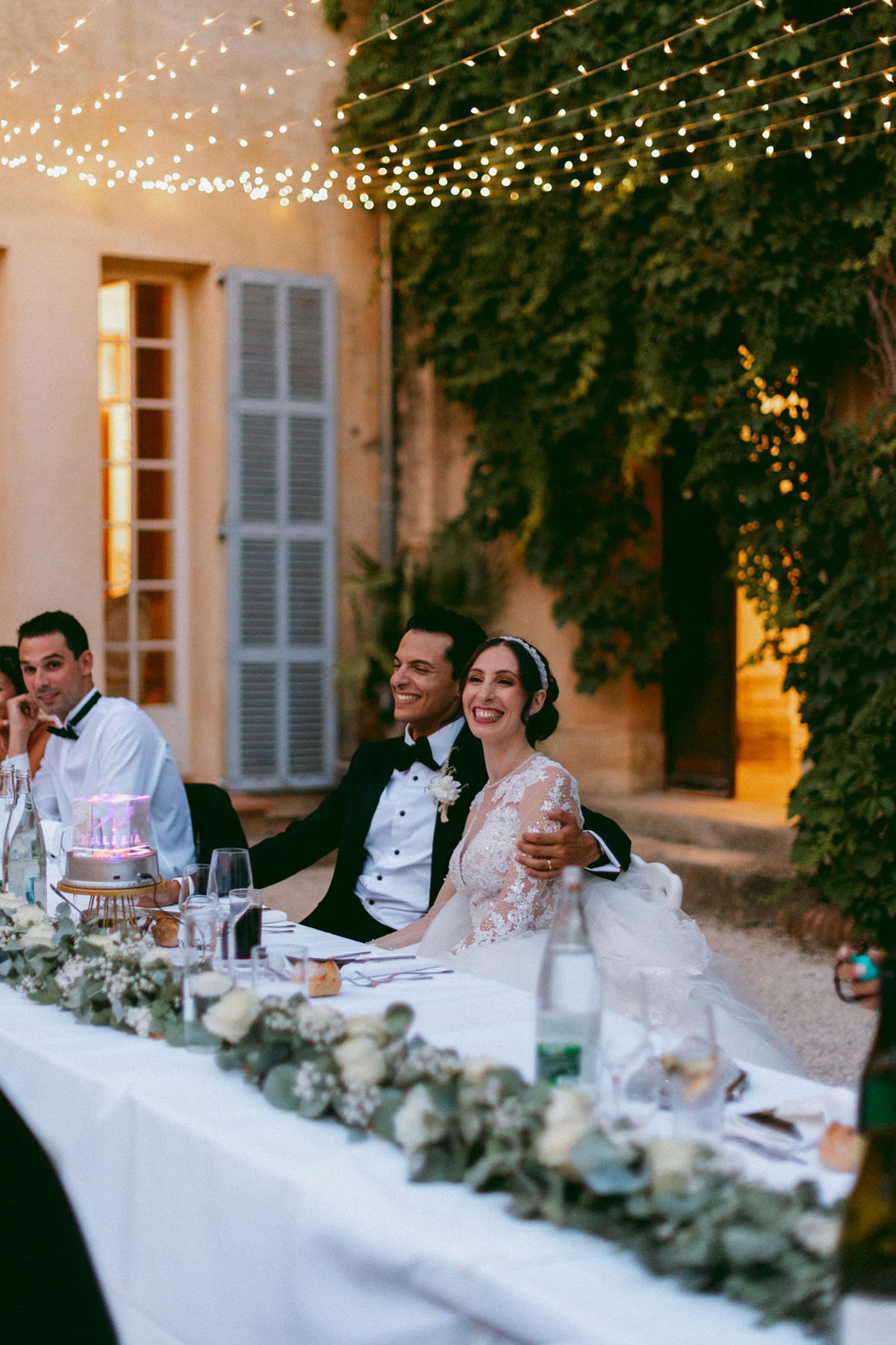 Ilenia and Dalil seated at the head of the courtyard table during dinner