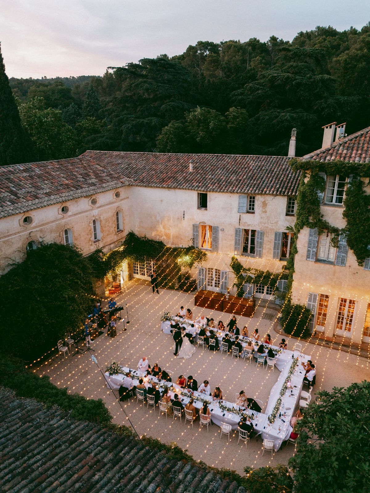 Aerial view of the courtyard dinner at dusk with guests at the long table