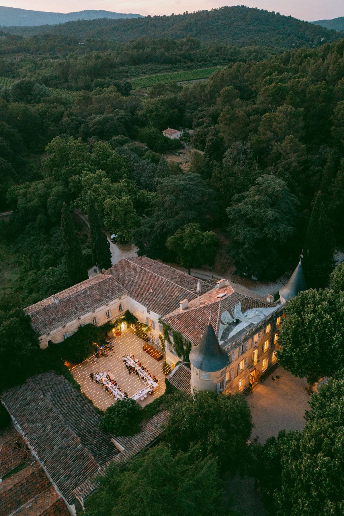 Aerial view of Château de Robernier at dusk with the courtyard dinner below