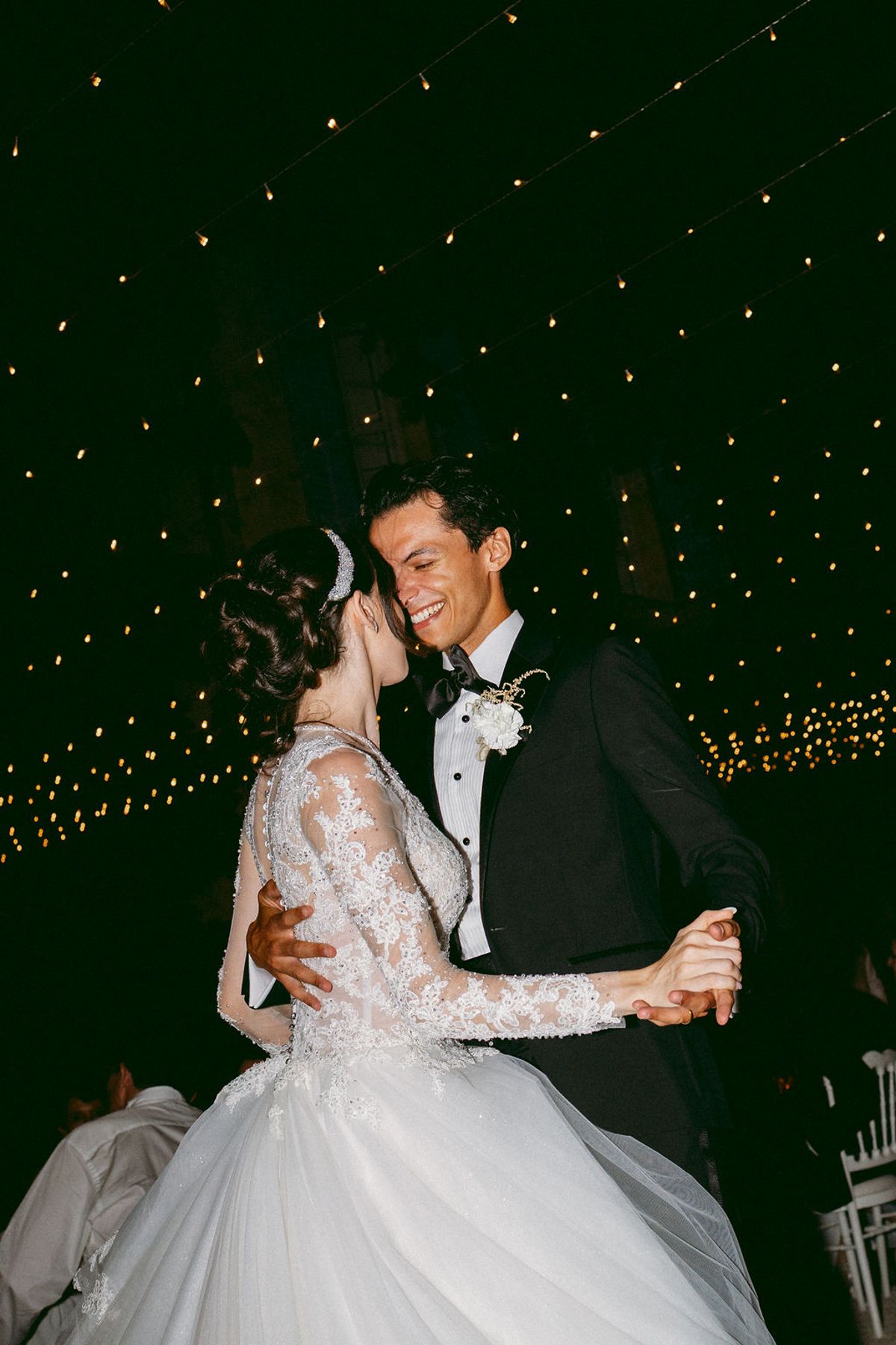 Ilenia and Dalil close together against a backdrop of fairy lights