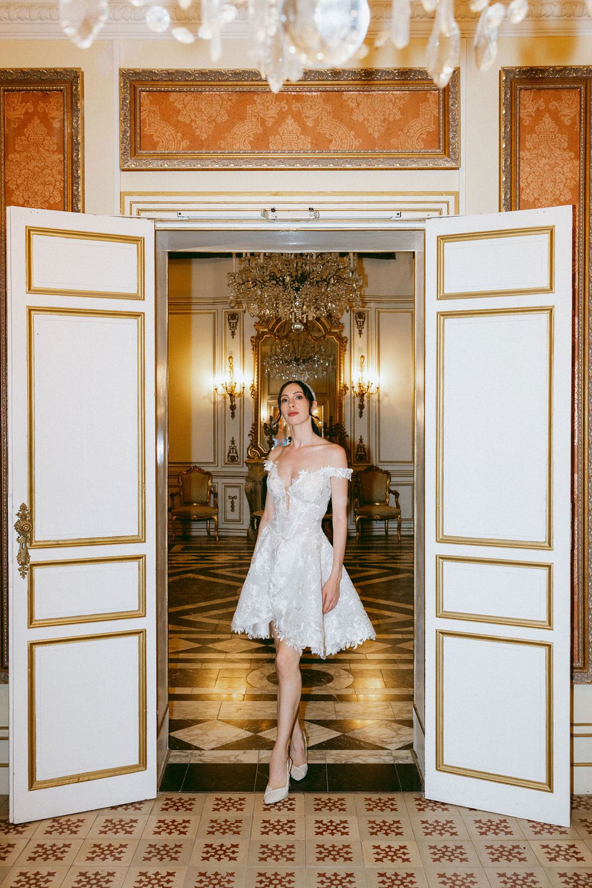 The bride in a short second dress in a doorway of Château de Robernier