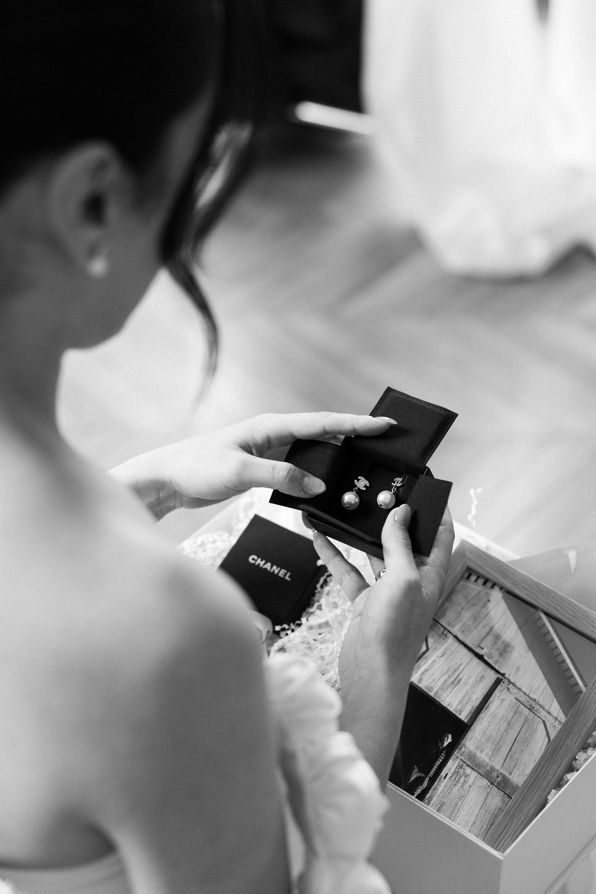 Black and white close-up of the bride opening a Chanel earring box