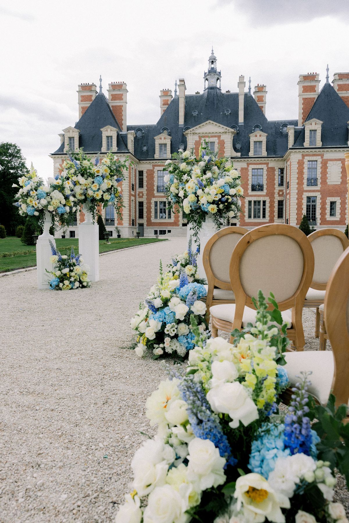 Blue hydrangea and white roses line the ceremony aisle towards the chateau