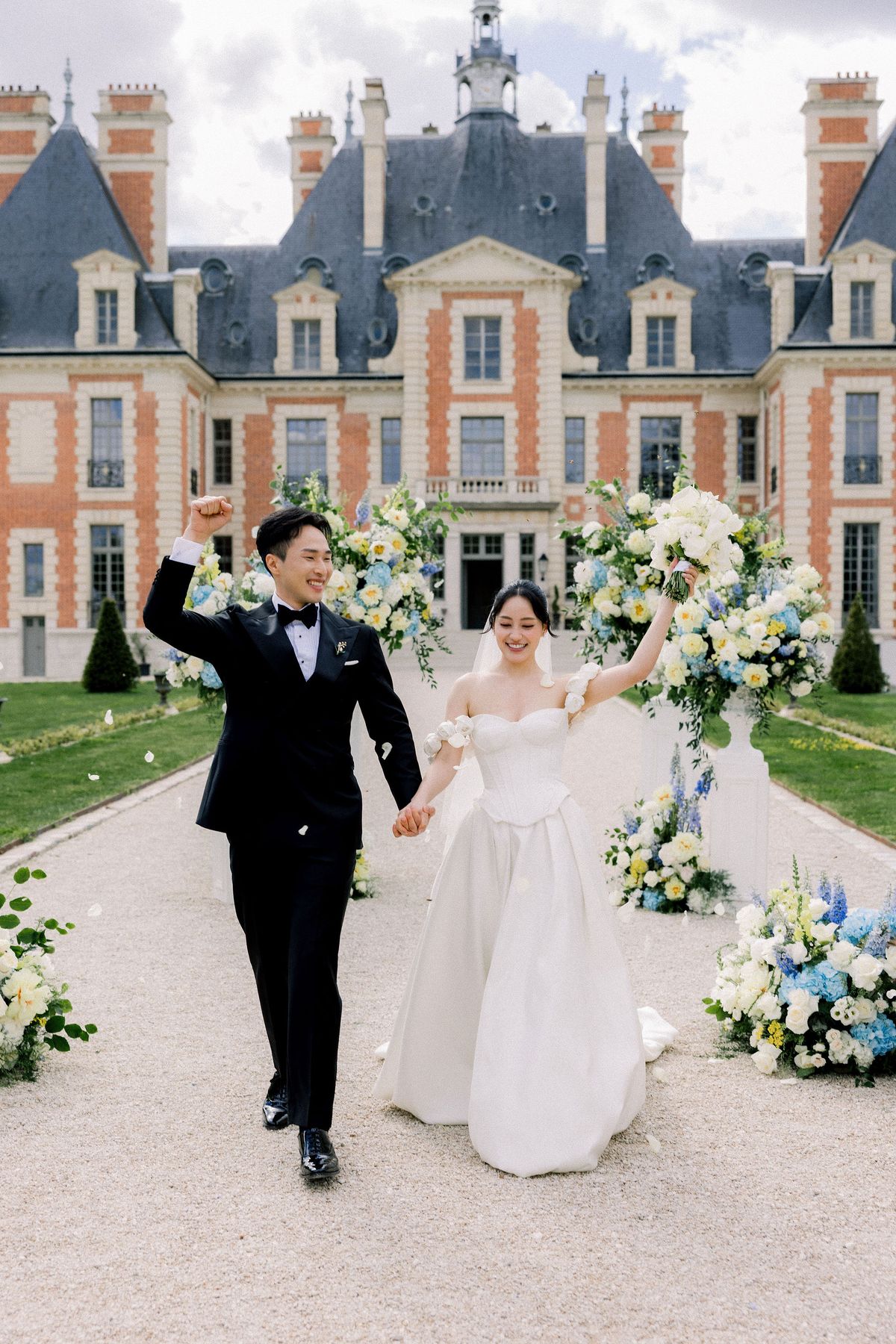 The couple walk back up the aisle hand in hand, both raising an arm