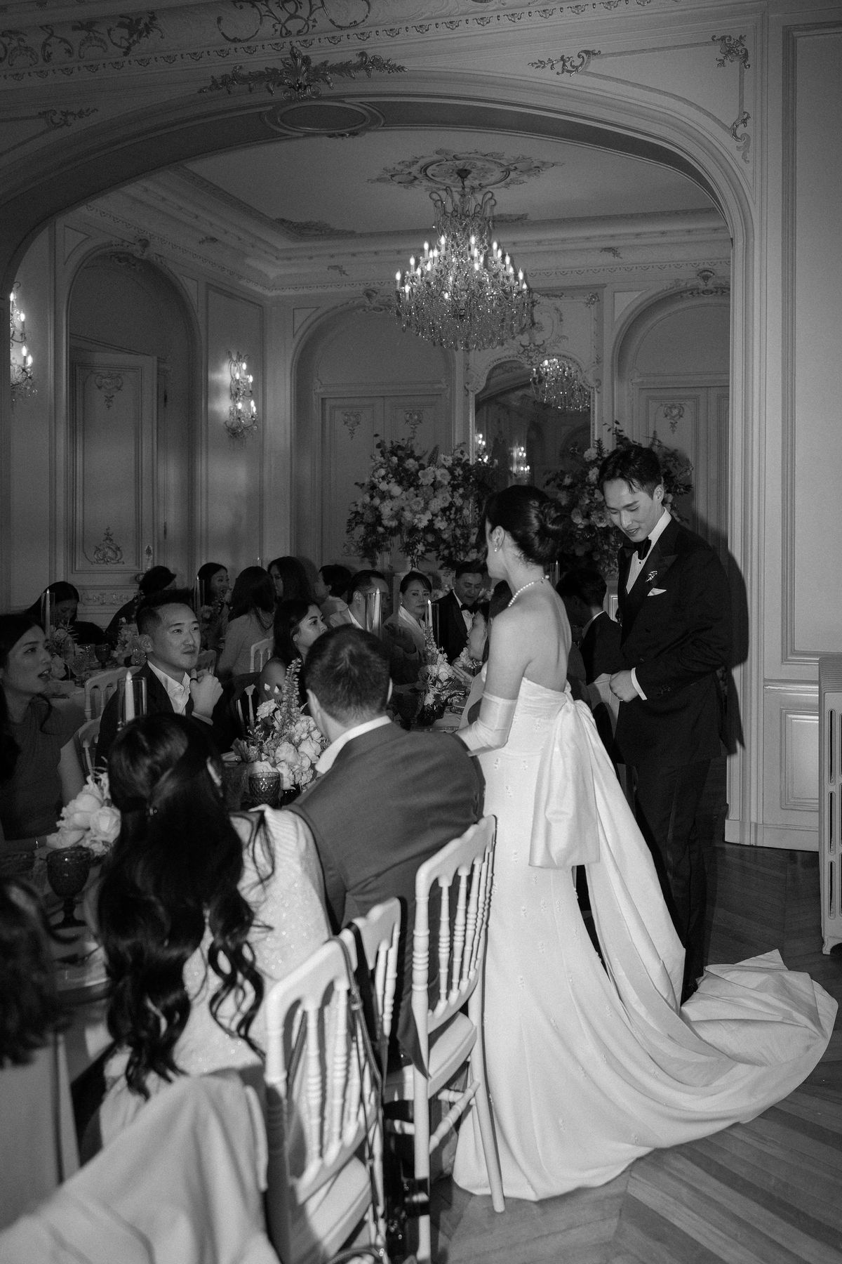 Black and white image of the couple standing among the seated dinner guests