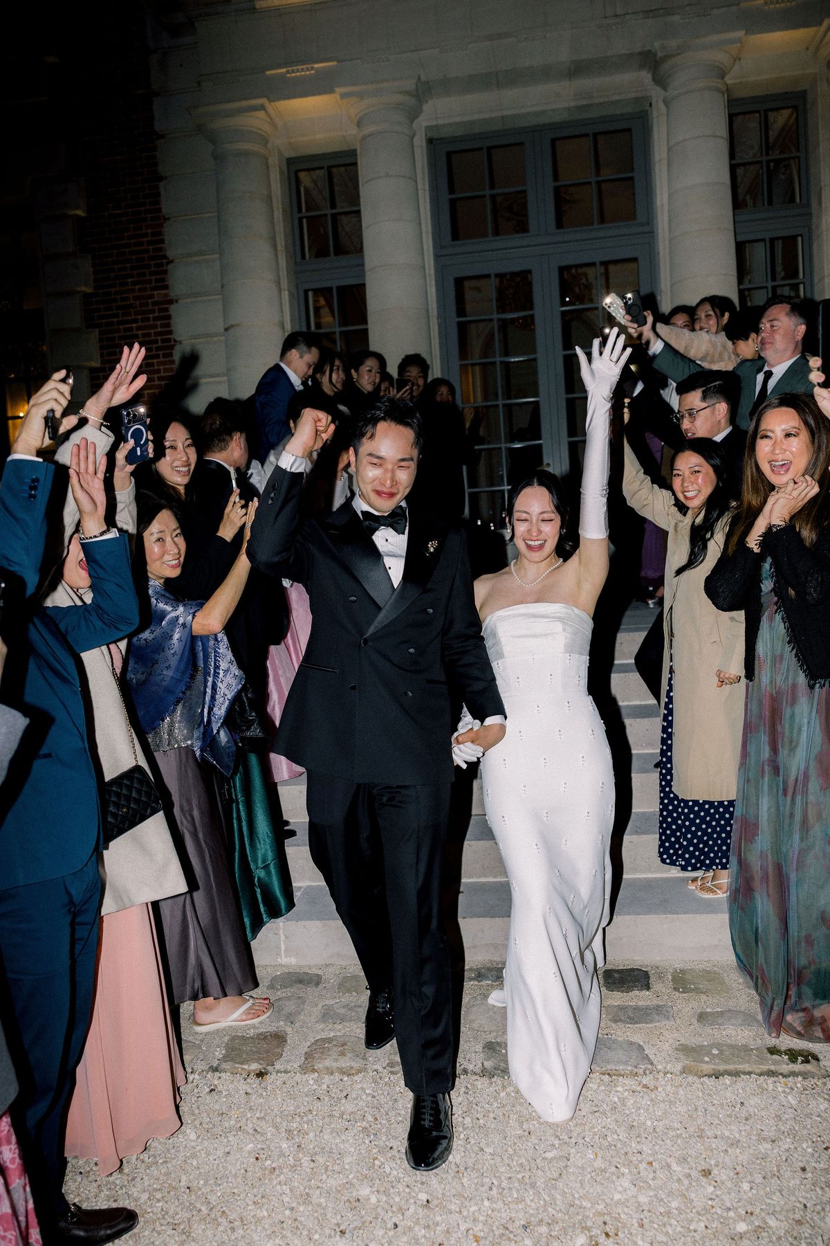 Guests cheer as the couple come down the chateau steps in the evening