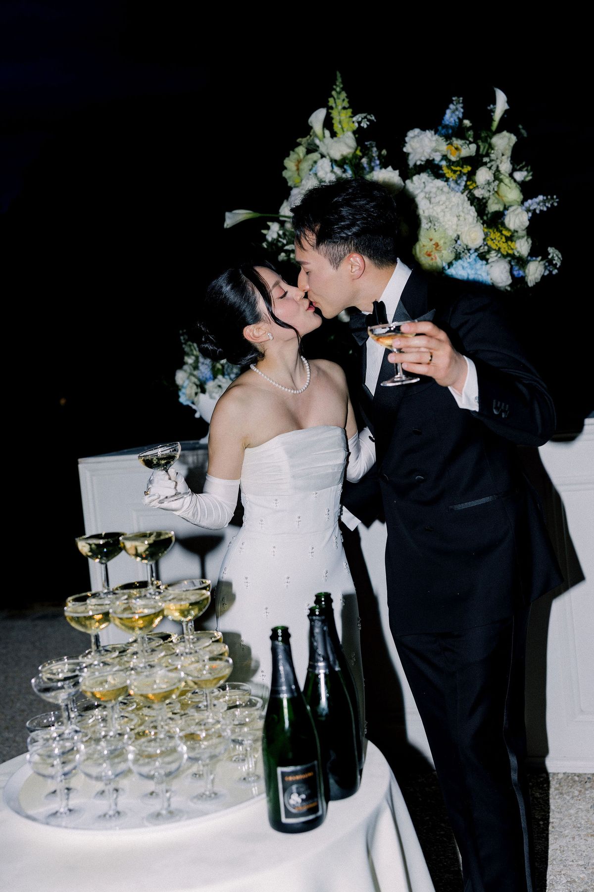 The couple kiss beside the champagne tower