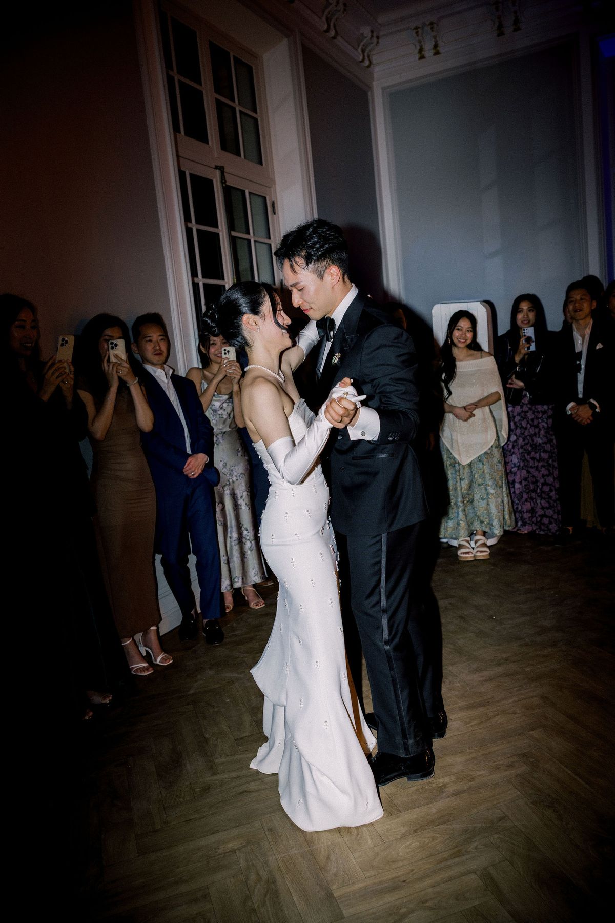 The couple dance together as guests watch from the edge of the room