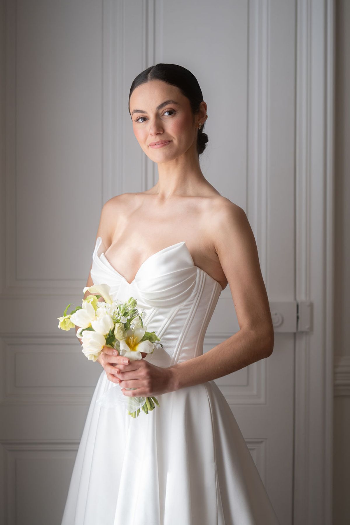 Portrait of a dancer in a structured satin gown holding a small spring bouquet