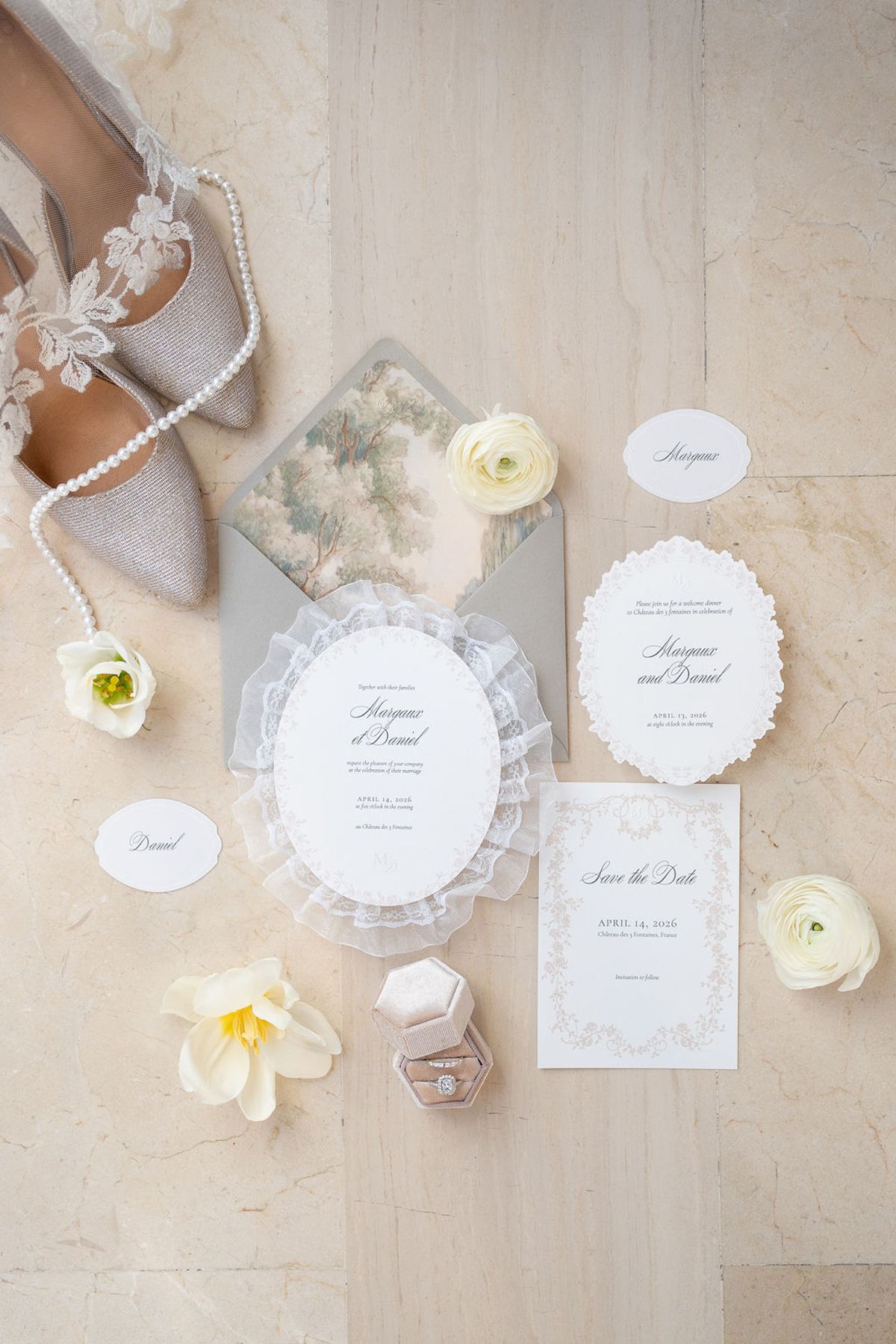 Flat lay of embellished heels, pearl strand, ranunculus and letterpress stationery on stone