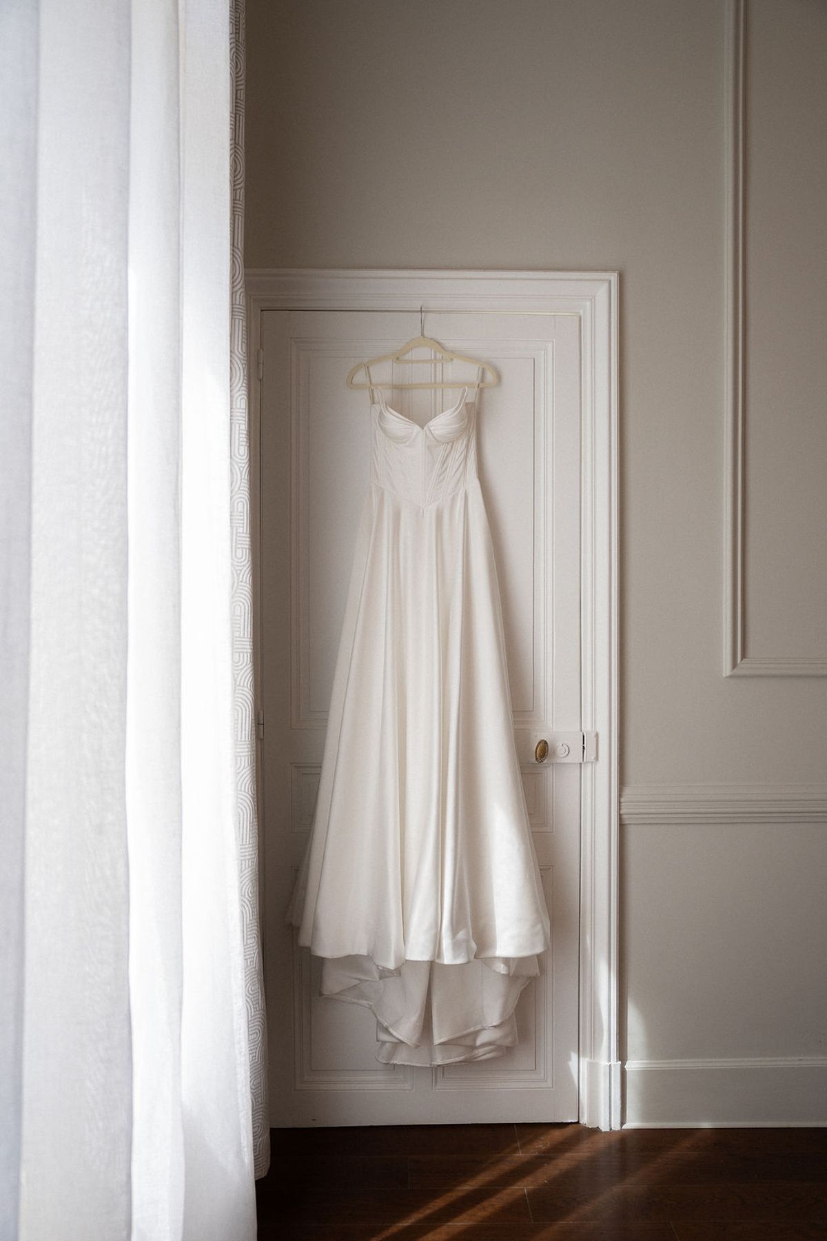 Silk gown on a hanger against a curtained window in a panelled room