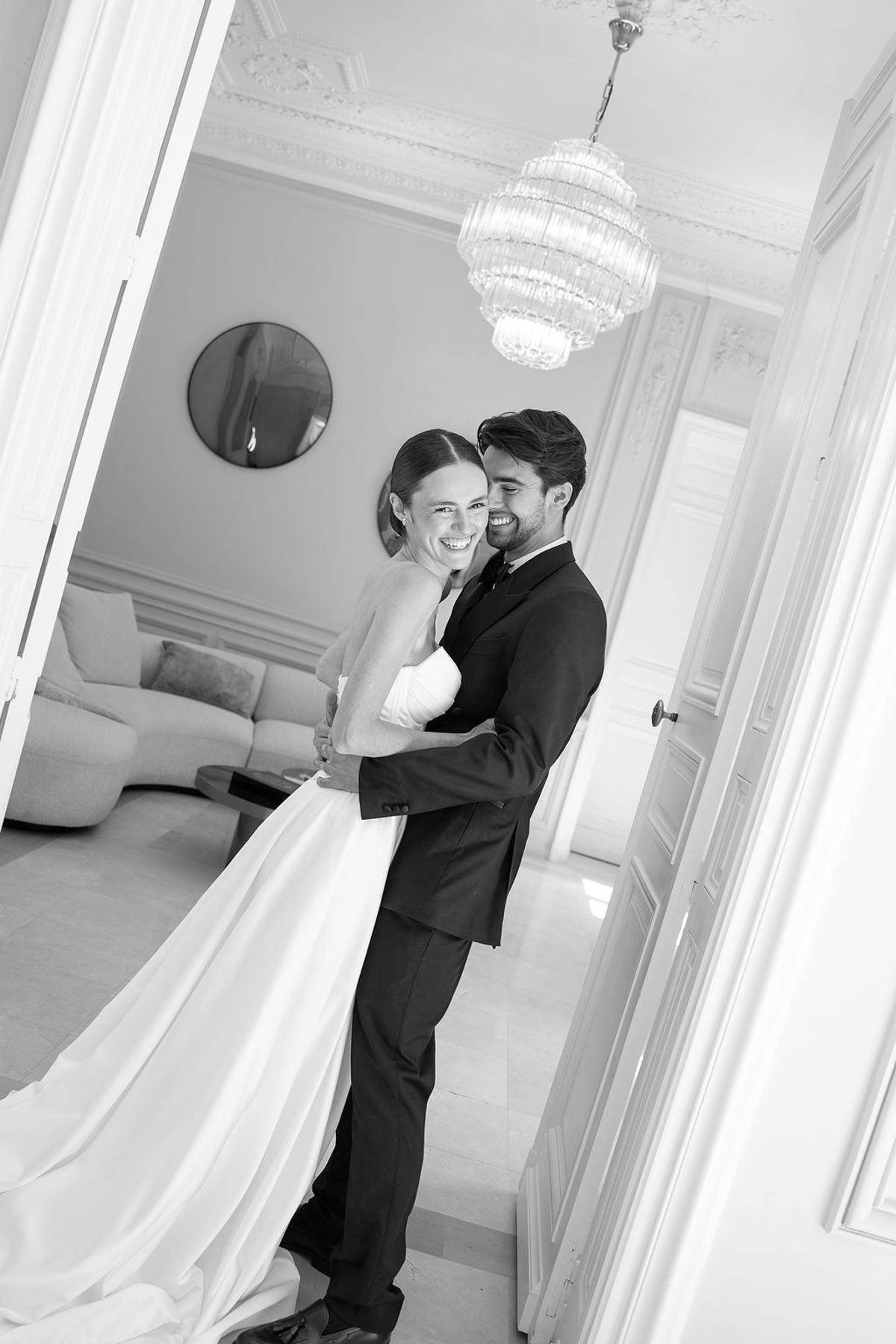 Black and white frame of two dancers turning together in a panelled salon