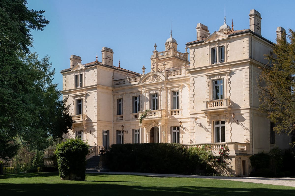 Wide view of Château des Trois Fontaines and its lawns from the park