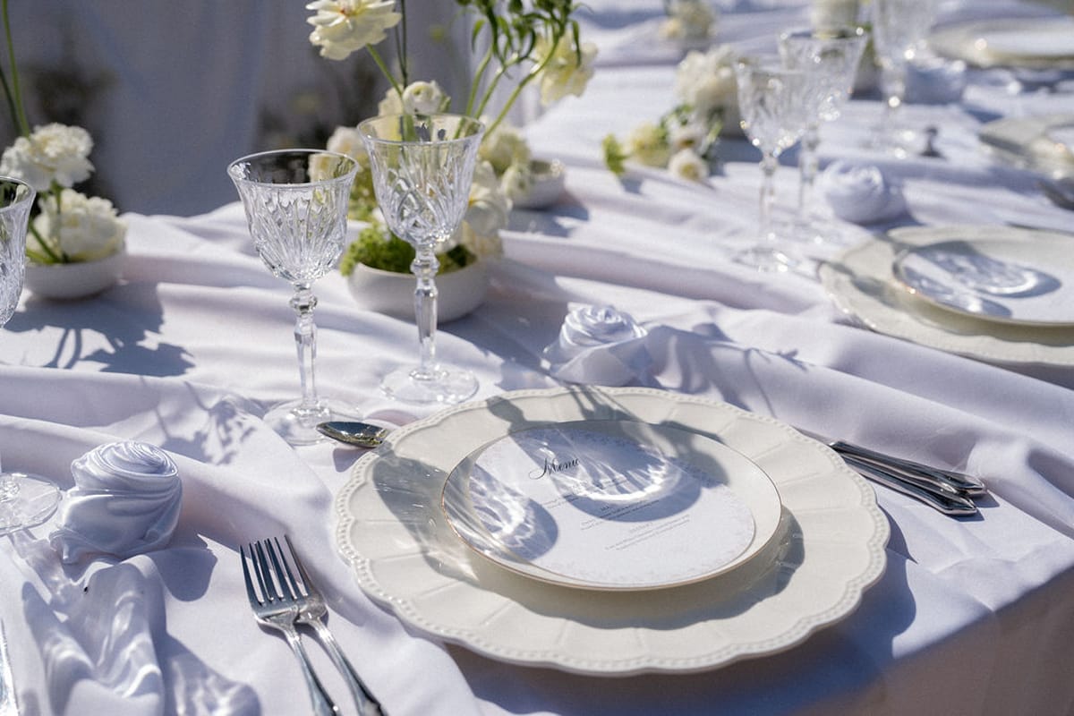 Place setting with crystal glassware, white linen and a scalloped charger