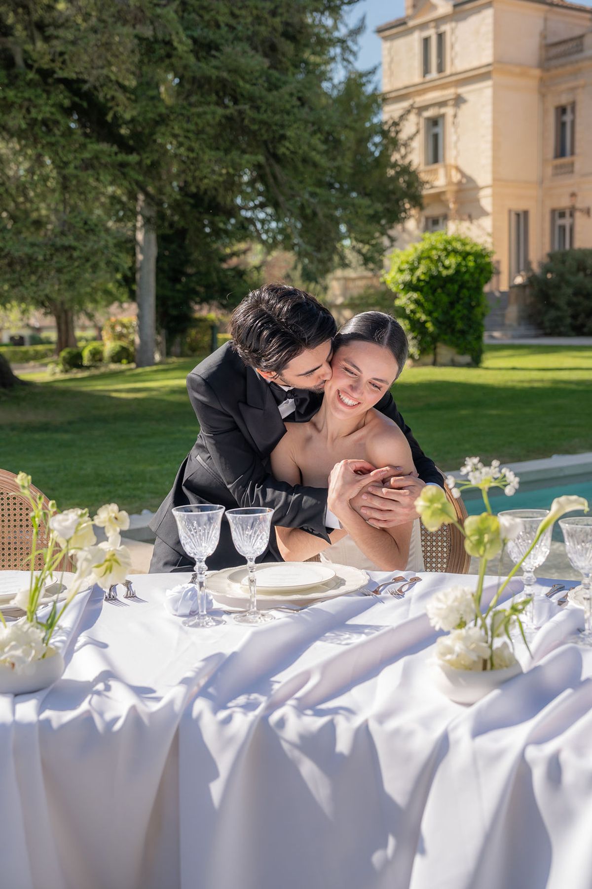 Two dancers seated at a set table on the lawn with Château des Trois Fontaines behind