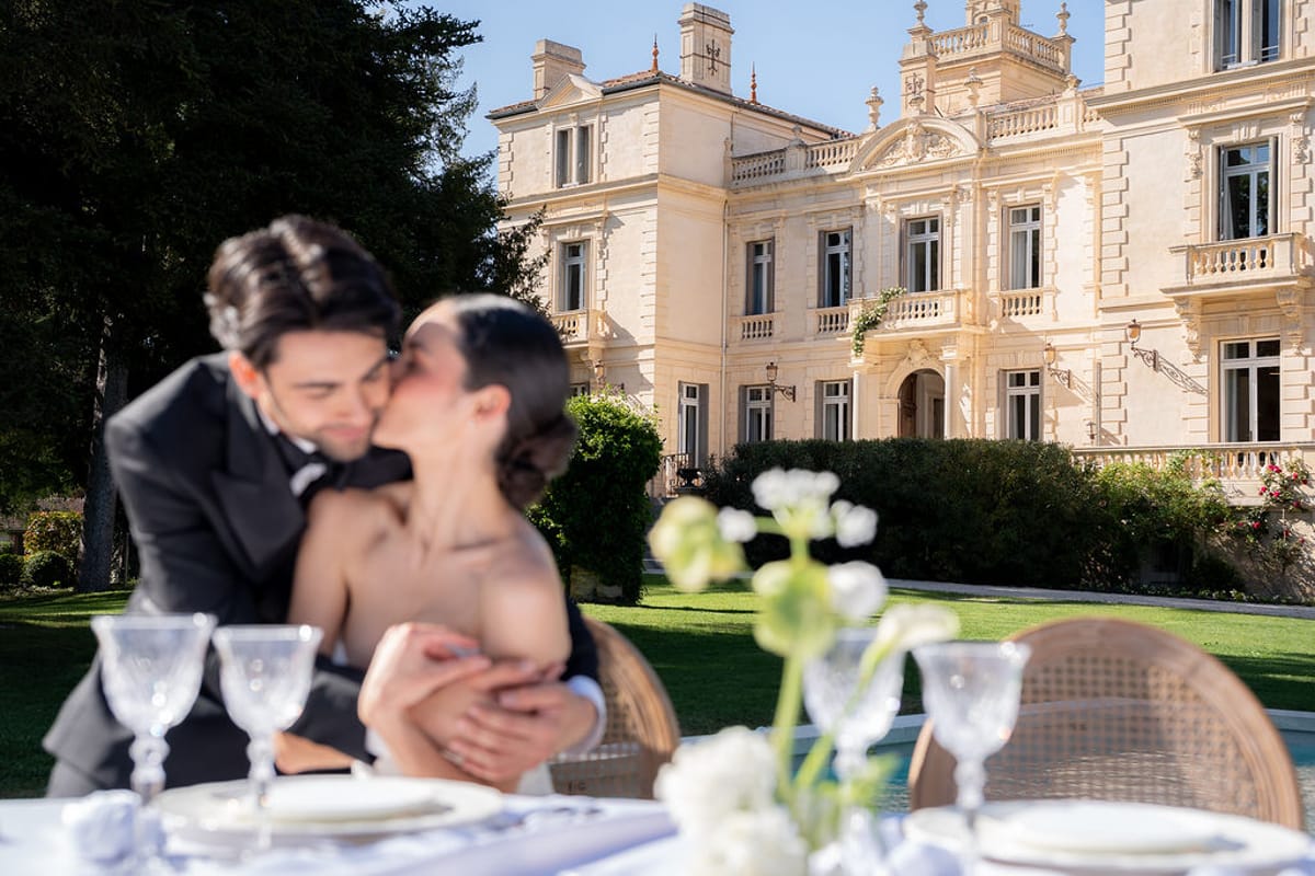 Two dancers embracing at a set outdoor table with glassware and white florals