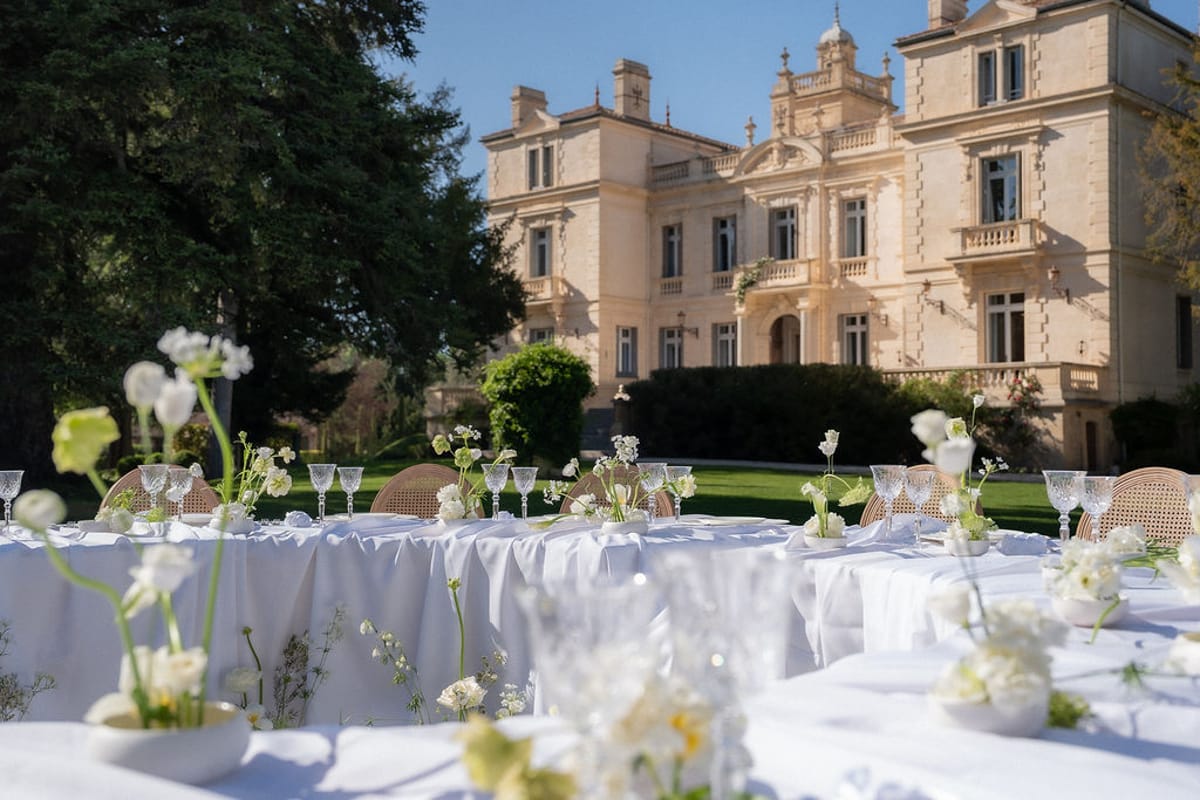 Long table set with candles and white florals on the lawn at Château des Trois Fontaines at dusk