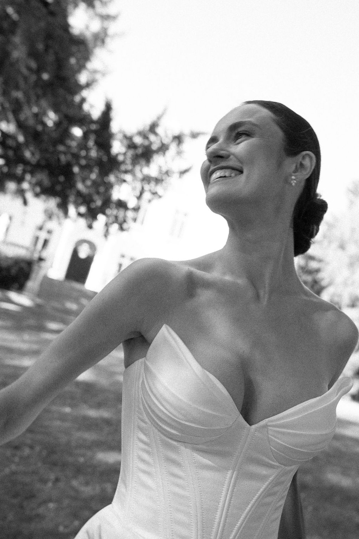 Black and white portrait of a dancer laughing, head turned over a corseted bodice