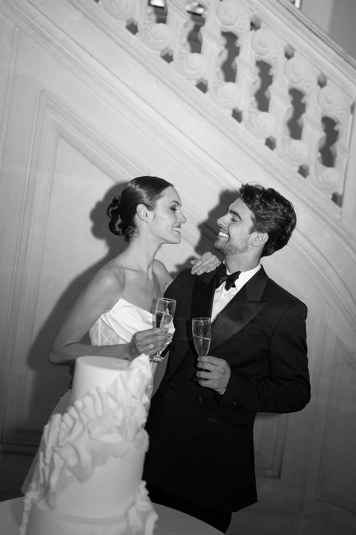 Black and white frame of two dancers with champagne on a carved staircase