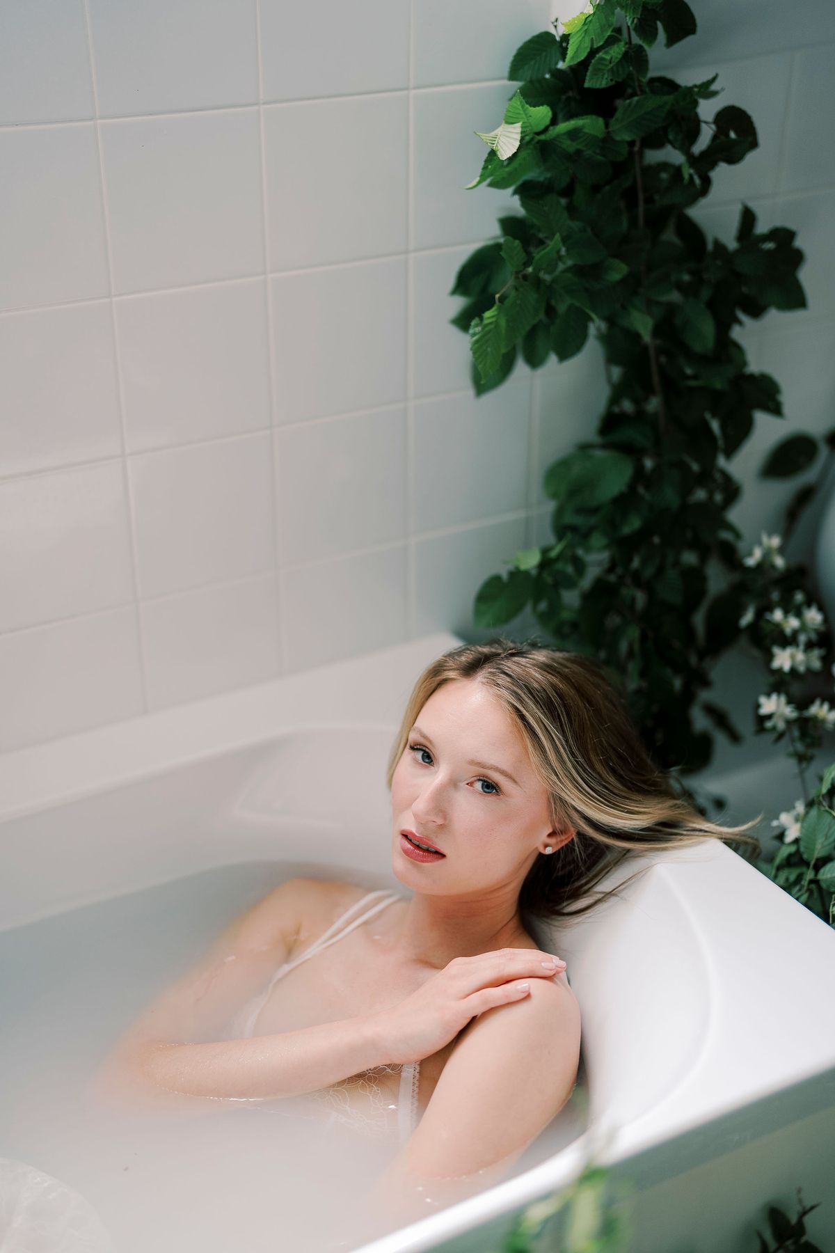 Close portrait of Amélie in the bath with greenery trailing over the tub
