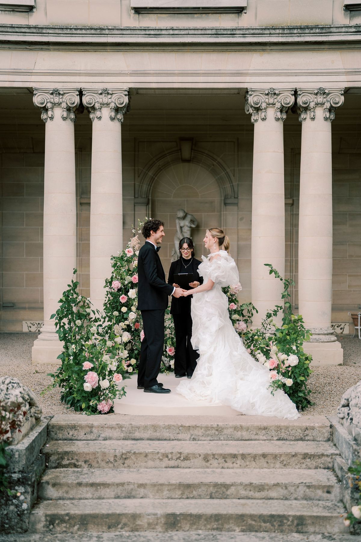 Celebrant standing between Amélie and Lucien on the circular platform before the peristyle columns