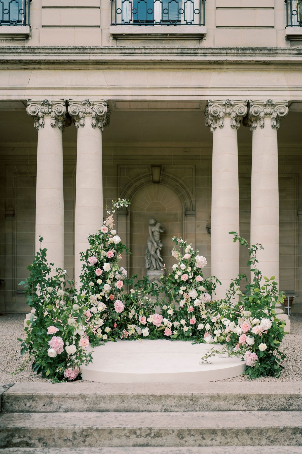 The columned peristyle of Château du Prieuré, the circular platform and flower installations before it