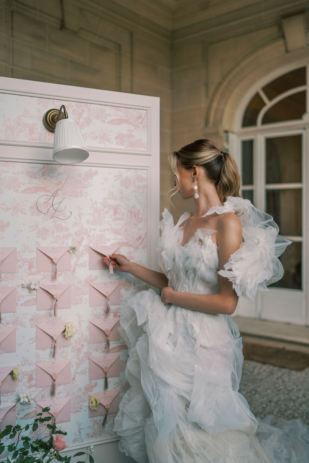 Amélie reaching for an envelope on the toile de Jouy seating chart