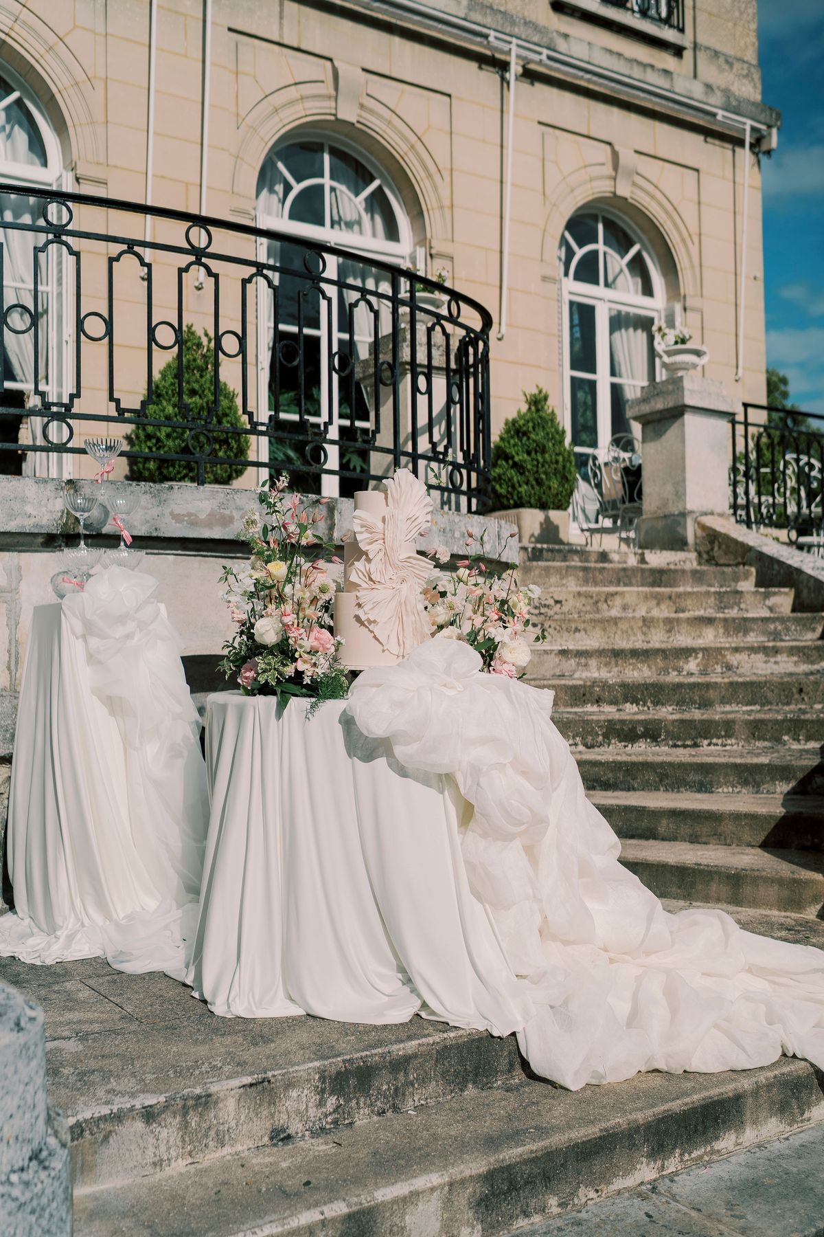 Curved stone terrace steps and arched windows of Château du Prieuré, a draped cake table on the steps
