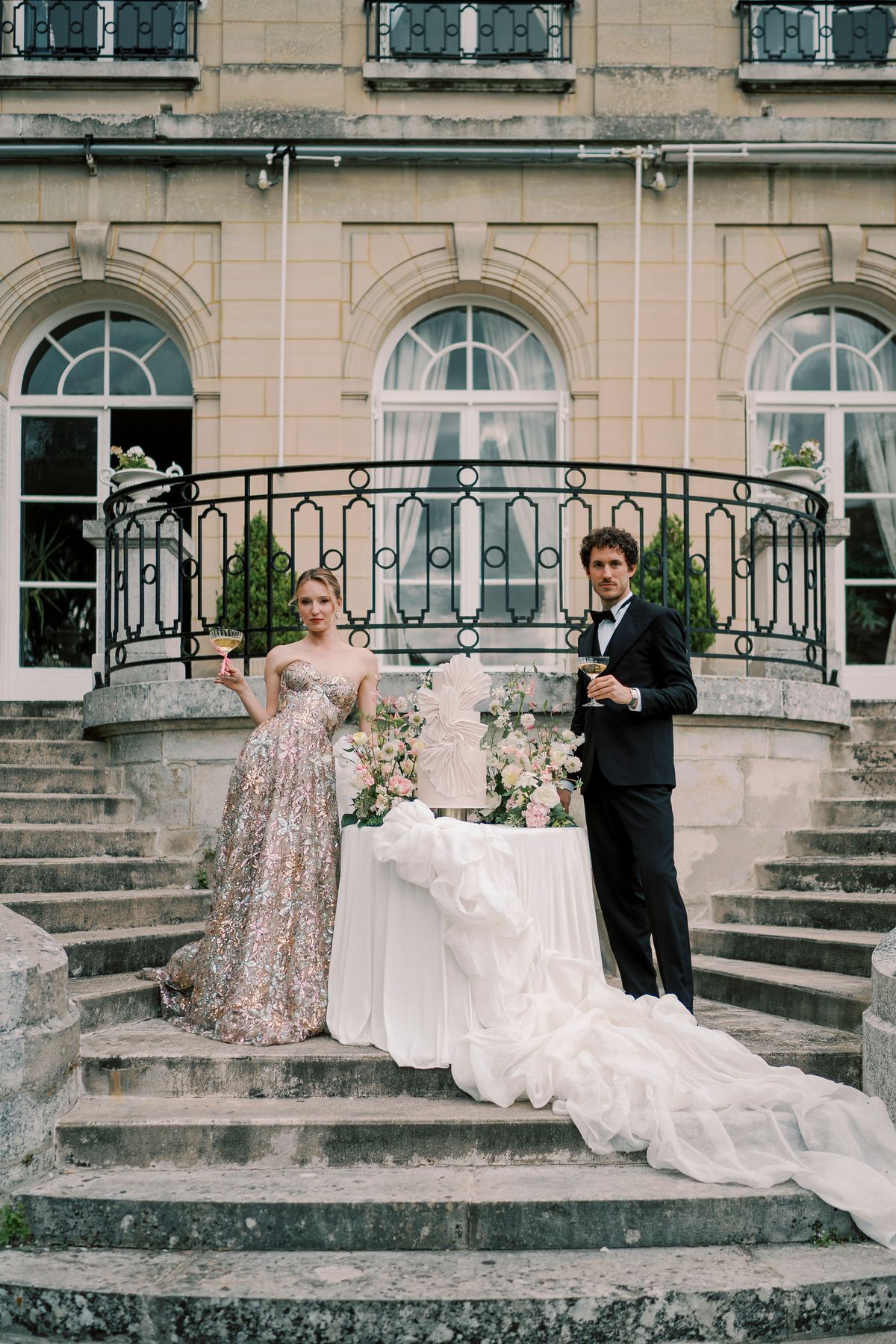 Amélie and Lucien with the cake table on the stone terrace steps of Château du Prieuré