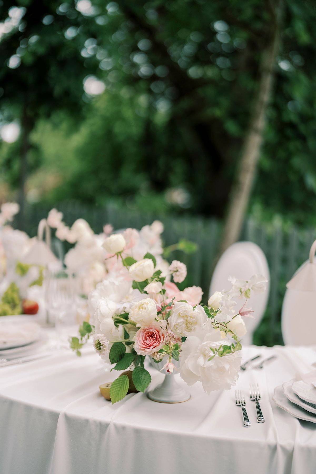 Low arrangement of roses and sweet peas on the ivory-linen dinner table