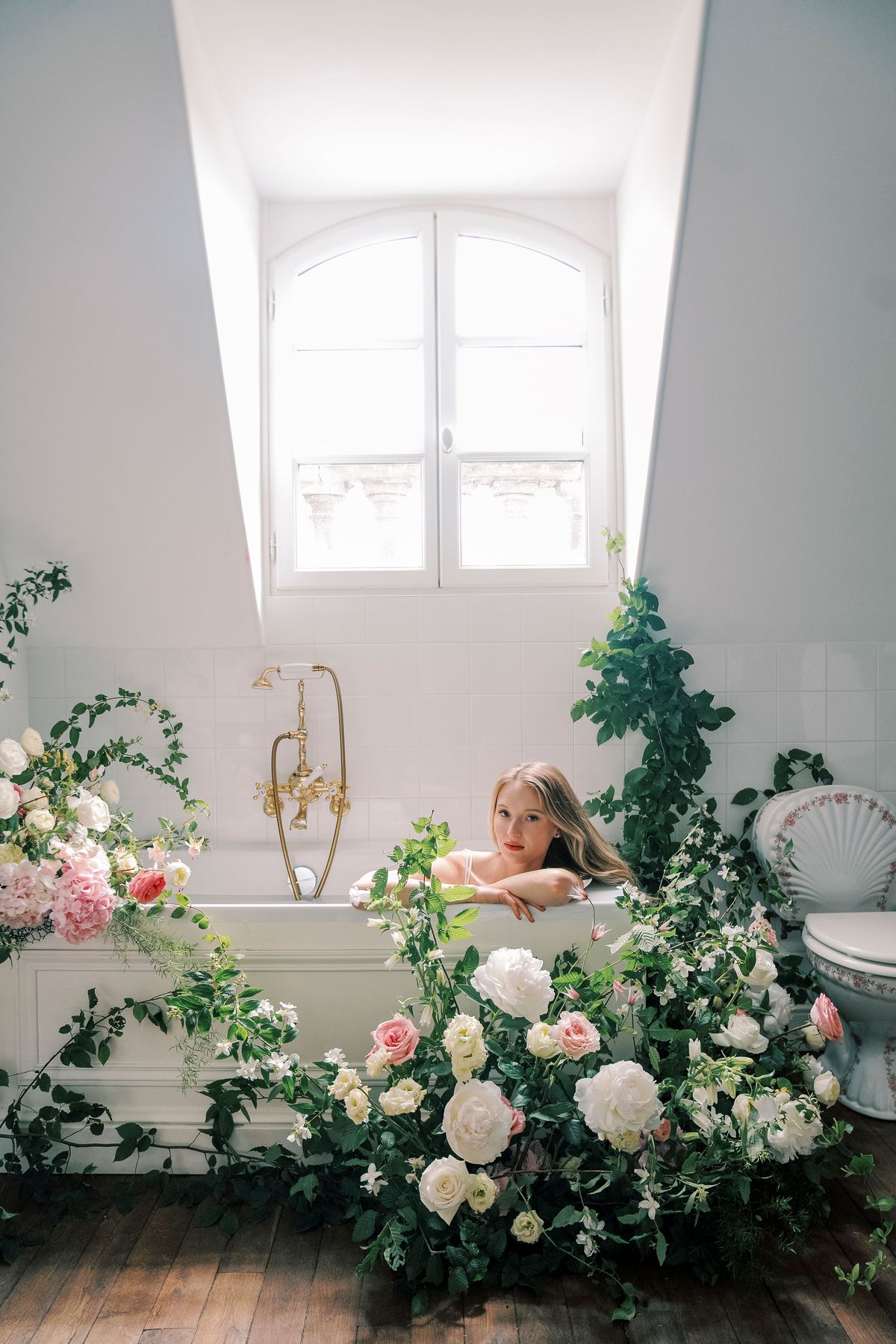 Amélie in the bath, framed by climbing greenery and white and pink roses