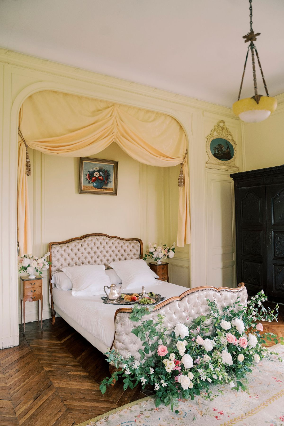 Canopied bed with a breakfast tray, roses and greenery banked along its foot, Château du Prieuré